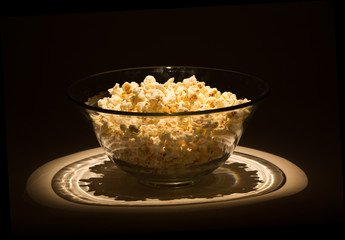 Popcorn in glass bowl in the dark