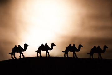 Figurines of camels on yellow background