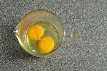 Two raw eggs in a measuring cup on a Grey worktop