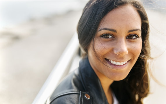 Portrait of smiling young woman with freckles and nose piercing
