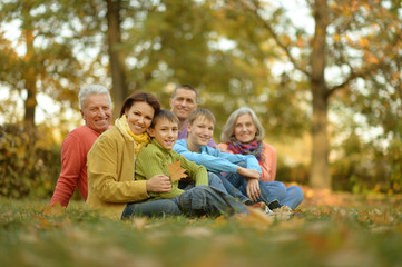 Naklejka na ściany i meble Family relaxing in autumn park