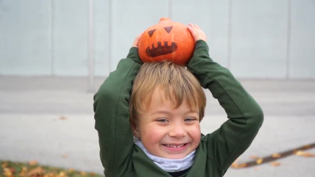 junger bub spielt mit k&uuml;rbis zu halloween
