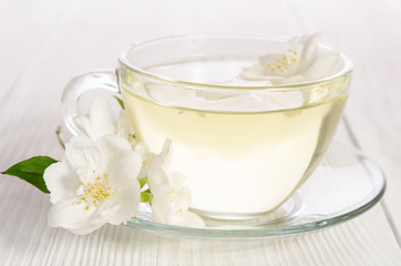 Obraz na płótnie Canvas Glass cup of tea with jasmine on the white wooden background