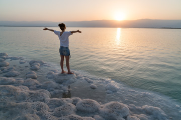 Girl meets sunrise on the shore the Dead Sea in Israel