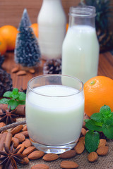 Almond milk in glass bottle with almond nuts on wooden table.