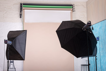 Fototapeta premium Empty photo studio with lighting equipment and paper background ready for photoshoot.