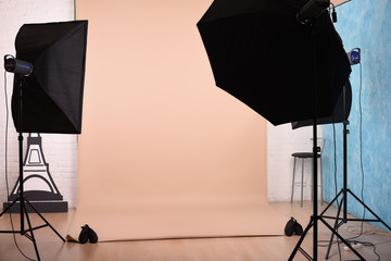 Empty photo studio with lighting equipment and paper background ready for photoshoot.