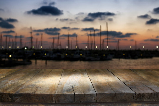 image of wooden table in front of abstract blurred yachts