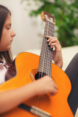 Cute little girl practicing her guitar lessons at home