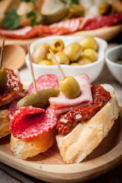 Tapas with sliced sausage, salami, olives and parsley.