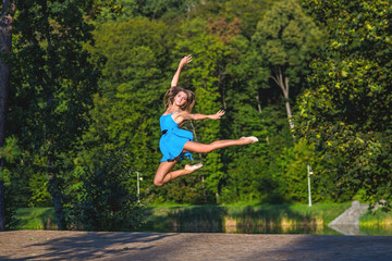 beautiful girl flies jump, nature in the background. Girl dressed in blue dress