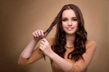 Beautiful woman with scissors cutting her hair