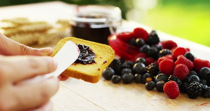 the hand of a young man in the morning for breakfast spreads of jam organic red fruits on a rusk . concept of organic jams and genuine and natural breakfast . Breakfast in the happy family