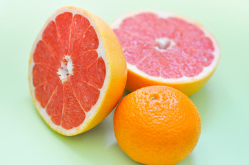 разные цитрусовые фрукты: грейпфрут, апельсин на зеленом фоне 