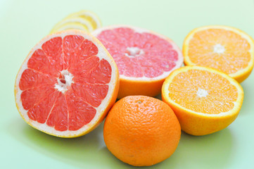 разные цитрусовые фрукты: грейпфрут, апельсин, лимон на зеленом фоне 