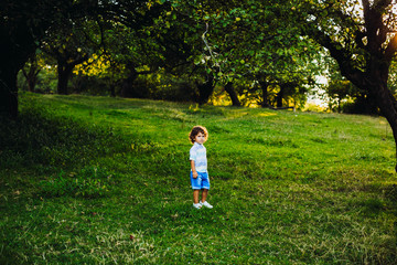 Cute little boy walking in a green park alone