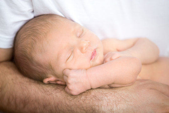 Brutal male hands gently holding sleeping newborn. Family, healthy birth concept photo, close up