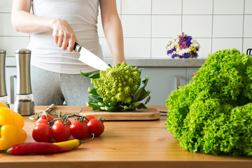 young woman cooking romanesco broccoli in the kitchen