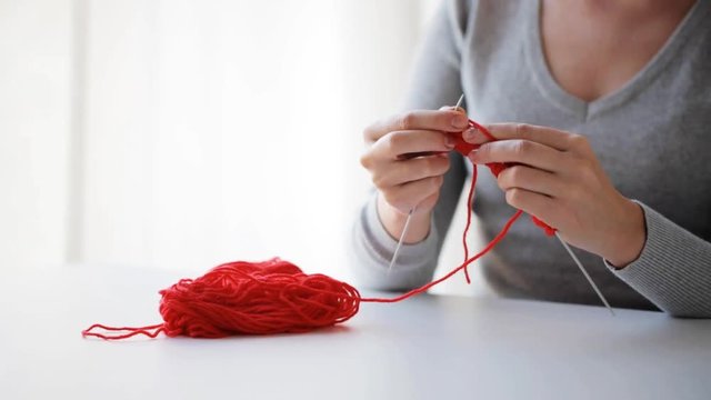 woman knitting with needles and red yarn