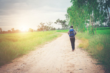 Obraz premium Back of young hipster man with backpack on his shoulder walking