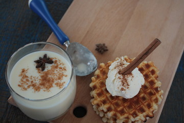 waffles with ice cream and milk, cinnamon, anise on blue wooden background. a magical dessert for Christmas
