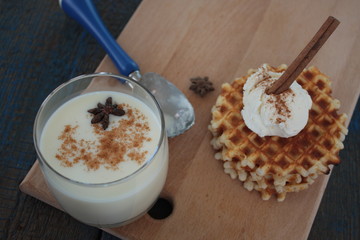 waffles with ice cream and milk, cinnamon, anise on blue wooden background. a magical dessert for Christmas
