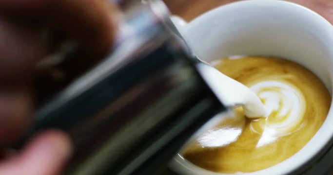 a bartender makes an artistic composition with fresh milk to make a cappuccino Italian quality, using Italian espresso. Italian concept, passion for work, breakfast and love for coffee and art.