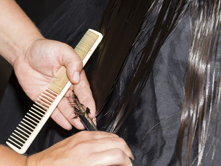 Female hairdresser hands are cutting hair tips.