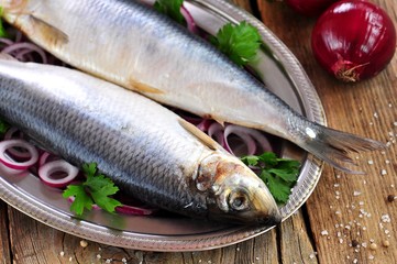 salted herring with red onion and parsley on the old wooden background.
