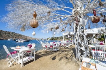 Informal beachside seating with decorative tree in a scenic tourist village near Bodrum, Turkey