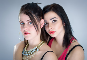 Studio portrait of two sensual girls isolated on grey background