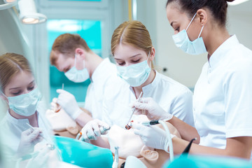 Students practicing on an artificial jaw and a dummy
