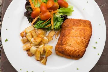 salmon steak with roast potato and salad