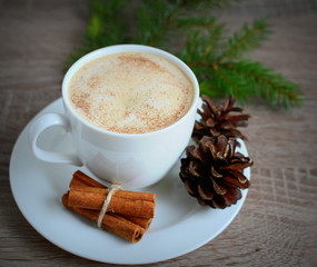 Cup of coffee and brown pine cone on wooden table