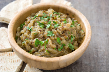Baba ganoush in wooden bowl and pita bread on wooden table

