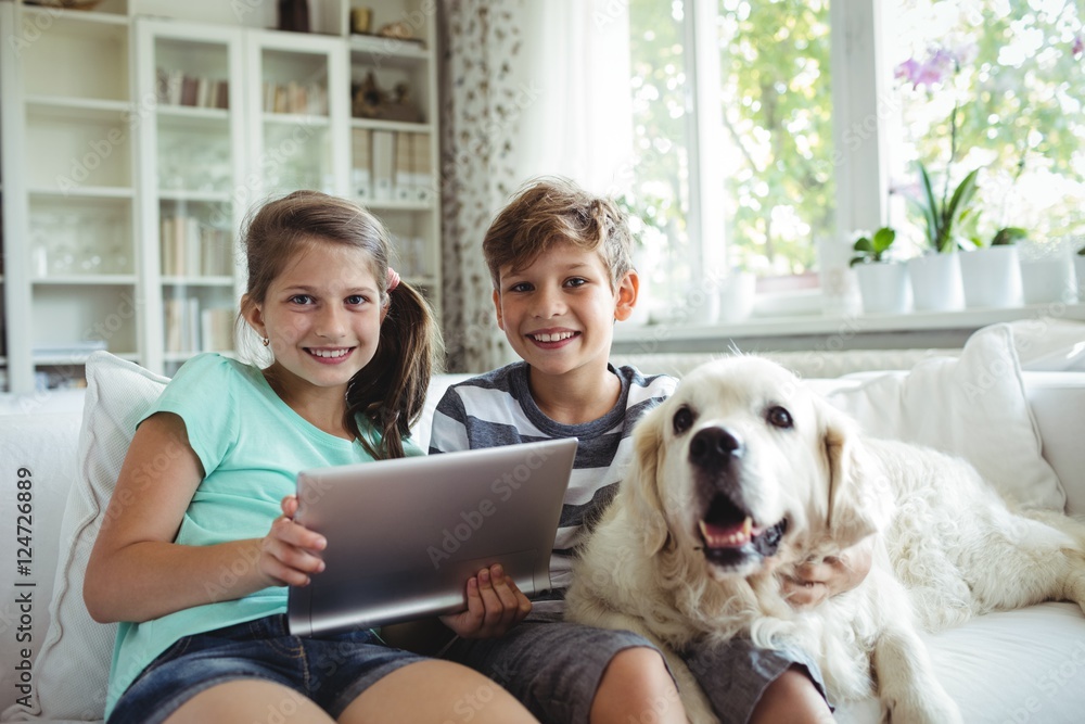 Poster children using digital tablet while sitting on a sofa