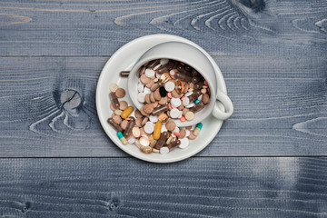 Medical capsules and tablets inside coffee cup
