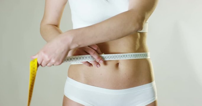  beautiful young woman measures the perfect body with a tape measure to understand the effects of diet and weight loss healthy diet and nutrition concept