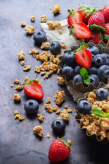 Homemade muesli granola in bowl with berries on rusty table