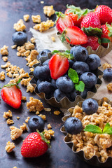 Homemade muesli granola in bowl with berries on rusty table