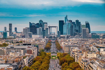 Fototapeta na wymiar La Defense Financial District Paris France in autumn. Traffic on Champs-Elysees with orange and yellow trees aside. Modern vs. Old architecture. Blue sky