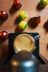 una tazza di caffe fragrante di mattina, che ha fatta con macchina del caffe. Su sfondo sono capsule colorati