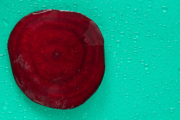 Beetroot. Cross section. Water drops. Green background. Top view