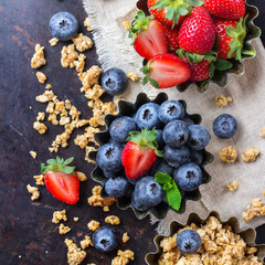 Homemade muesli granola in bowl with berries on rusty table