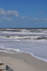 Fototapeta na wymiar Foaming waves on the beach rolling in