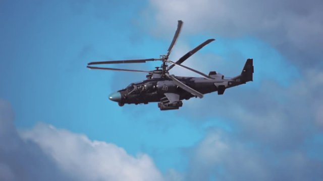 Reconnaissance and attack helicopter of the new generation Ka-52 "Alligator" flying on a background of blue sky and clouds. Includes audio. Contains audio