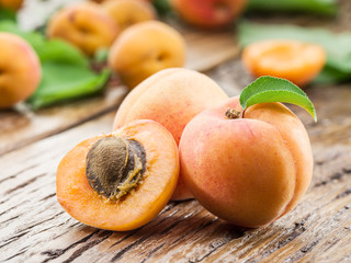 Apricots and its cross-section on the old wooden table.