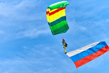 Парашютист летит на ярком цветном парашюте с флагом России