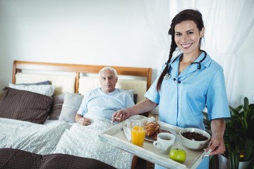 Obraz na płótnie Canvas Nurse serving breakfast to senior man