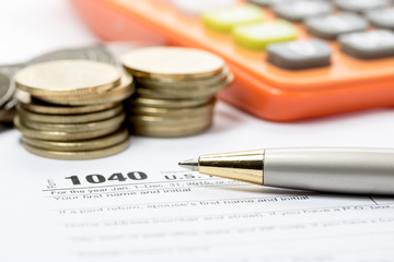  US tax form with pen and coins  selective focus / taxation conc